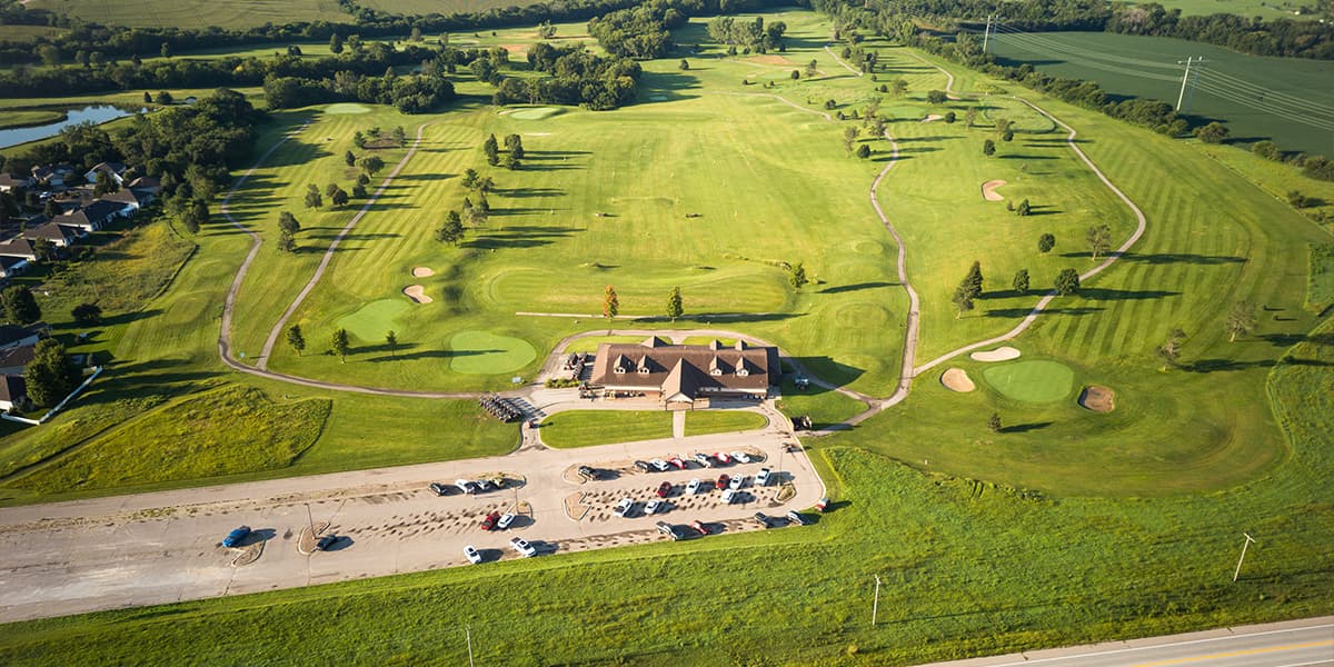 Aerial view of Crooked Creek Golf Club showcasing the clubhouse, championship golf course, rolling fairways, greens, and scenic landscape.